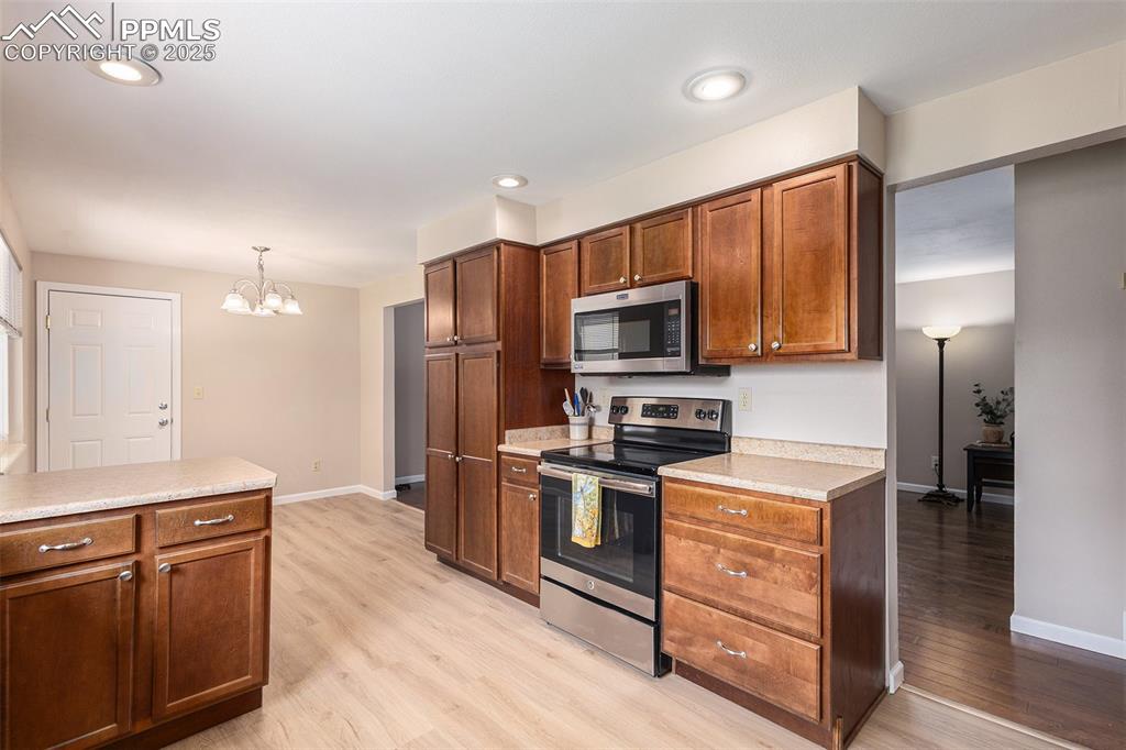 Image 10 of 29: Kitchen with stainless steel appliances, light wood-style LVP flooring, lig