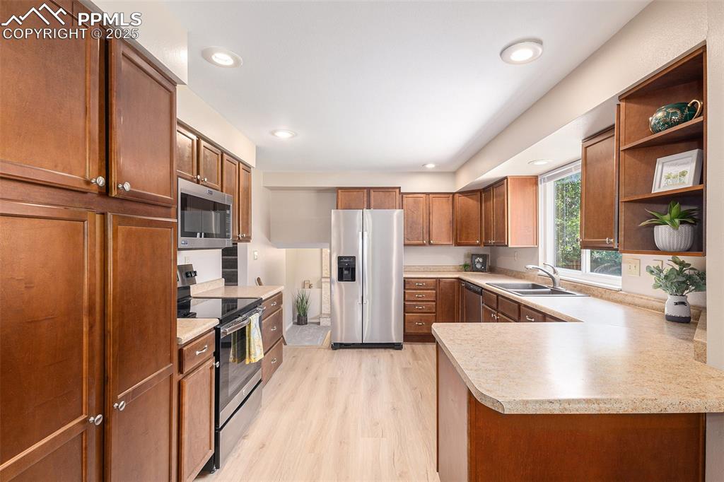 Image 11 of 29: Kitchen with stainless steel appliances, light countertops, light LVP floor
