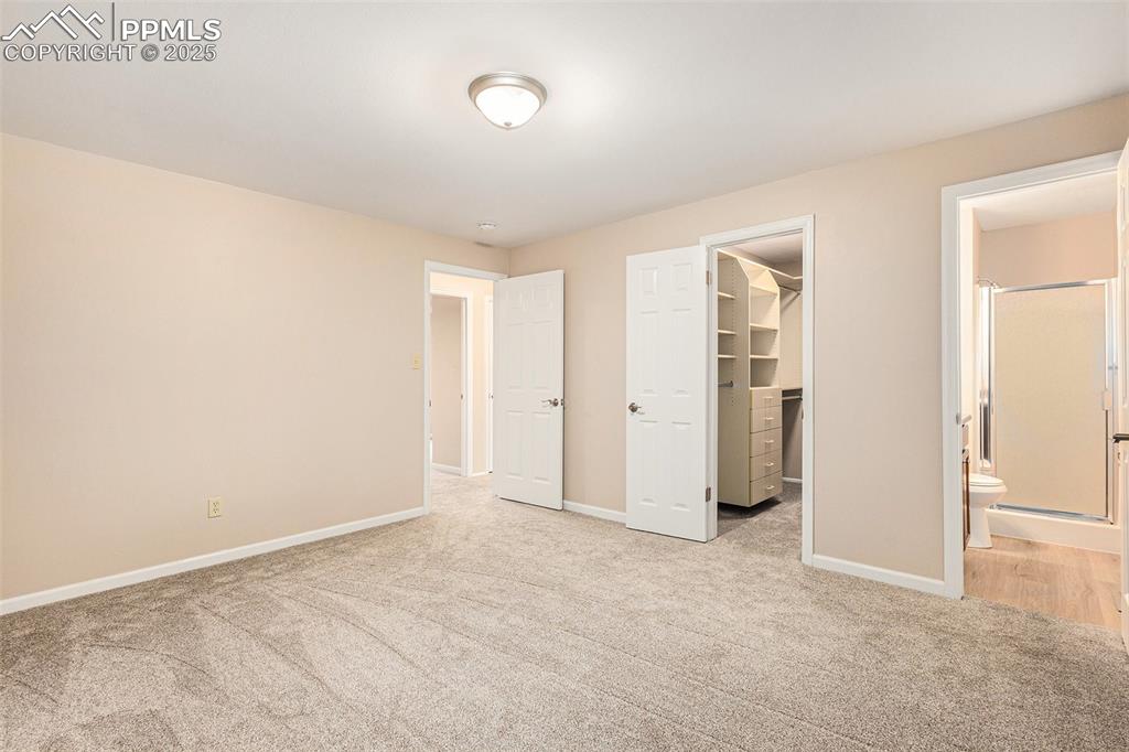 Image 14 of 29: Unfurnished bedroom featuring a walk in closet, carpet floors, and ensuite