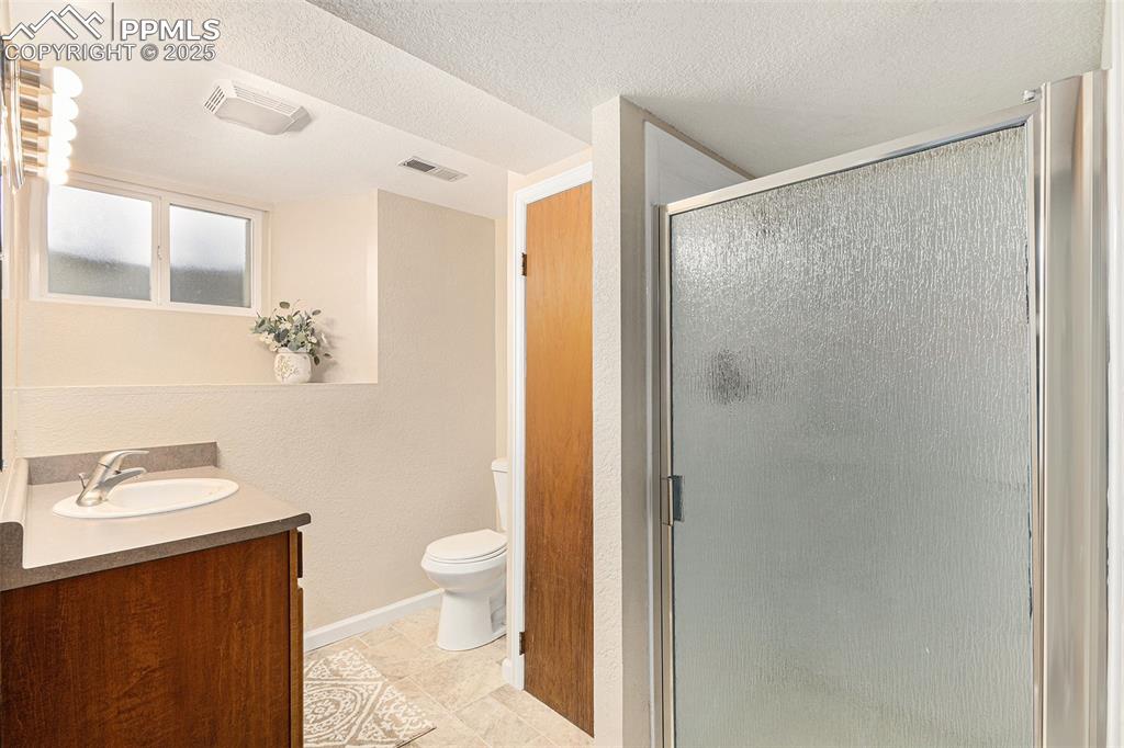Image 16 of 29: Bathroom with vanity, a textured ceiling, and a stall shower