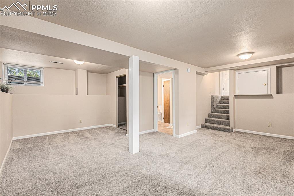 Image 26 of 29: Basement bedroom featuring new carpeting and stairs to family room