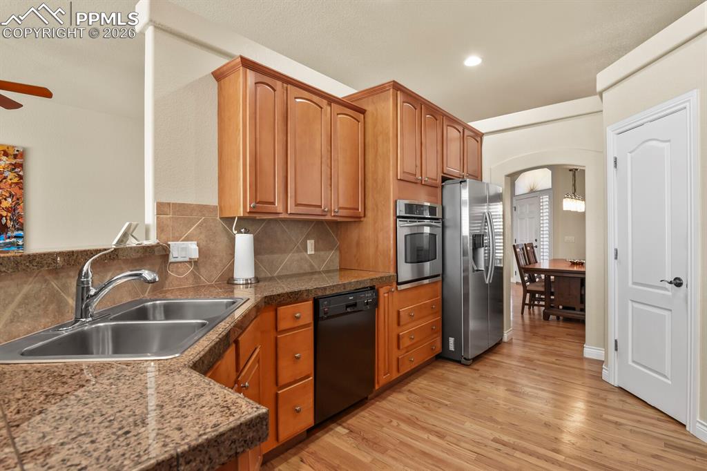 Image 10 of 46: The kitchen features granite tile countertops, wood cabinetry, stainless st