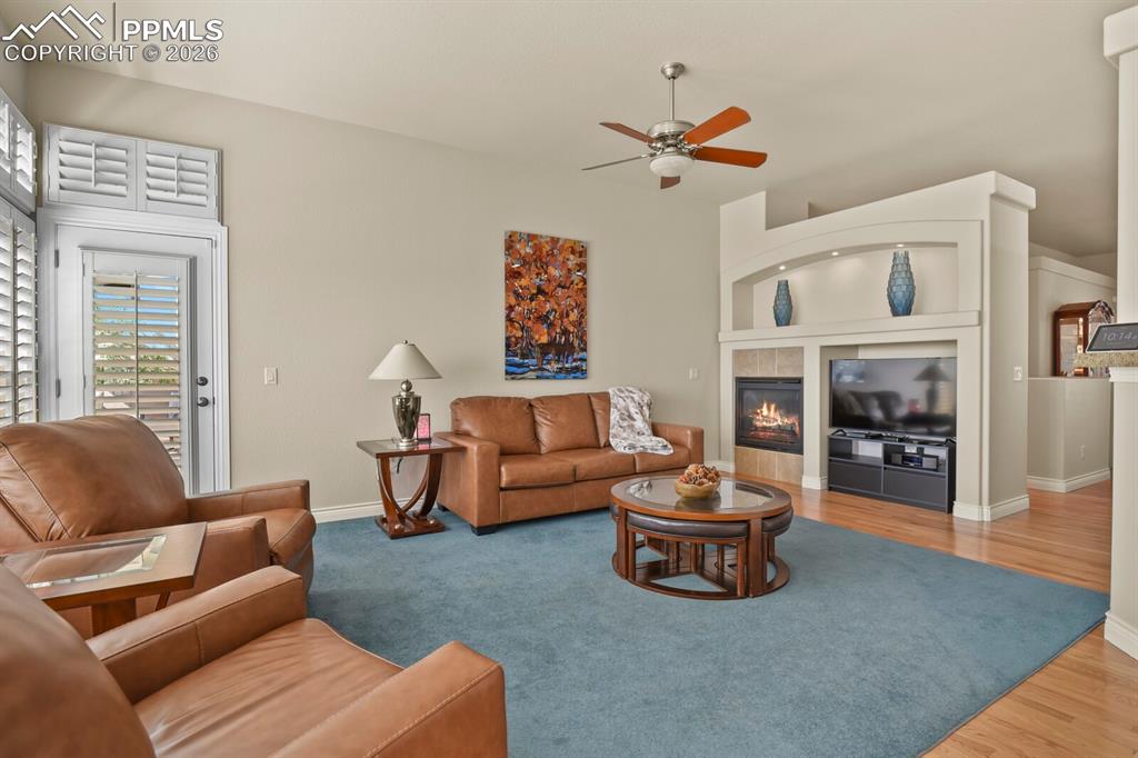 Image 13 of 46: Living area featuring a ceiling fan, a fireplace with a decorative mantel, 