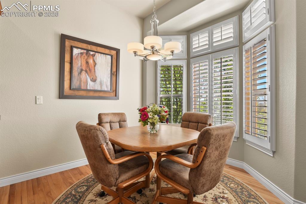 Image 15 of 46: This casual  dining area features hardwood flooring and an elegant chandeli