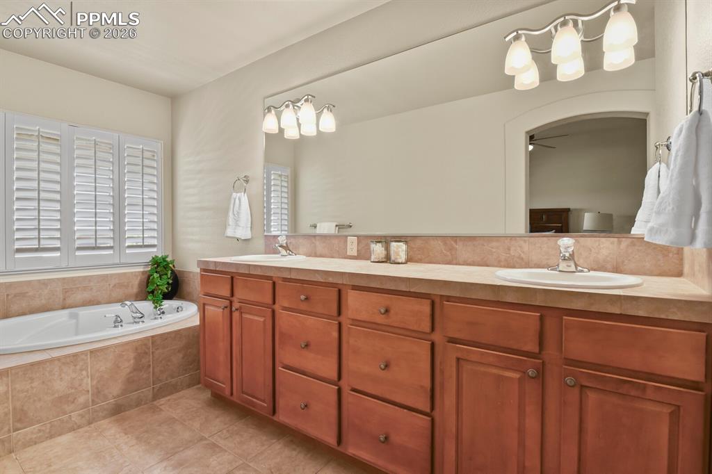 Image 20 of 46: Bathroom featuring a large corner soaking bathtub, wood vanity with two sin