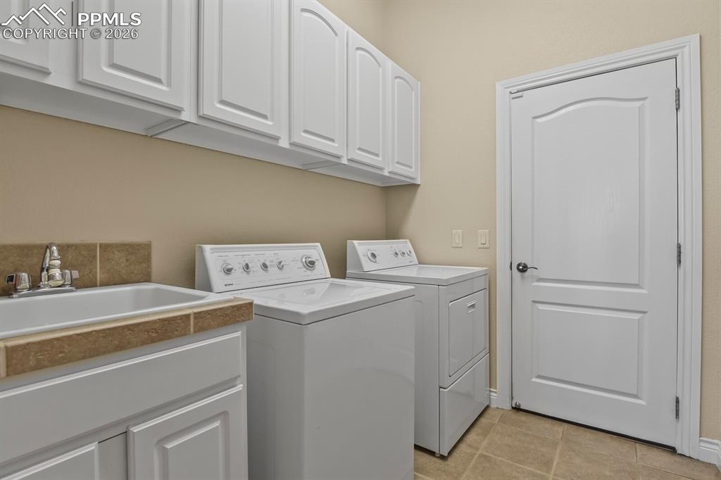 Image 25 of 46: Laundry room featuring a utility sink with a tiled backsplash, overhead whi