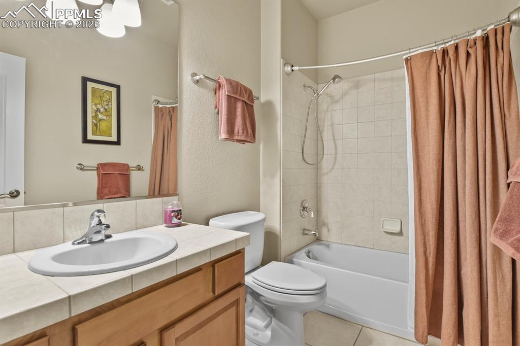 Image 33 of 46: The basement bathroom features a vanity with a tile countertop and an integ