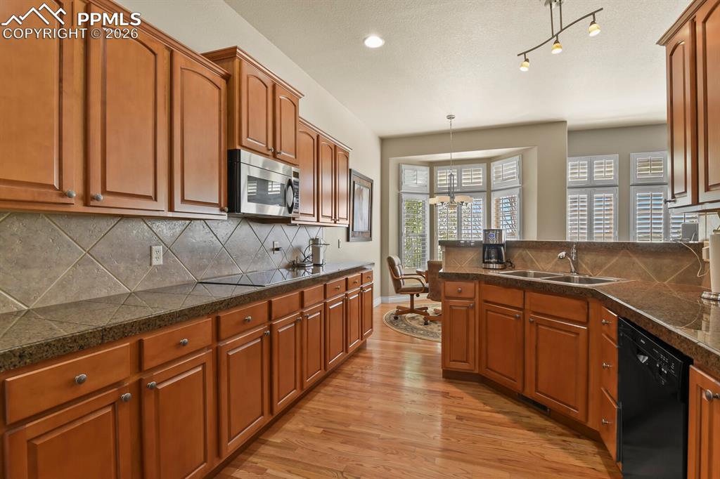 Image 8 of 46: Well-appointed kitchen featuring hardwood floors, warm-toned cabinetry, a t
