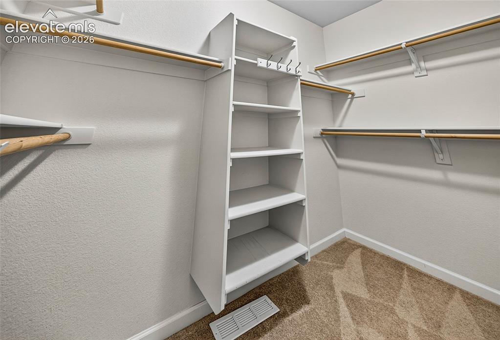 Image 24 of 43: Generously sized walk-in closet offers abdundant built-in shelving and stor