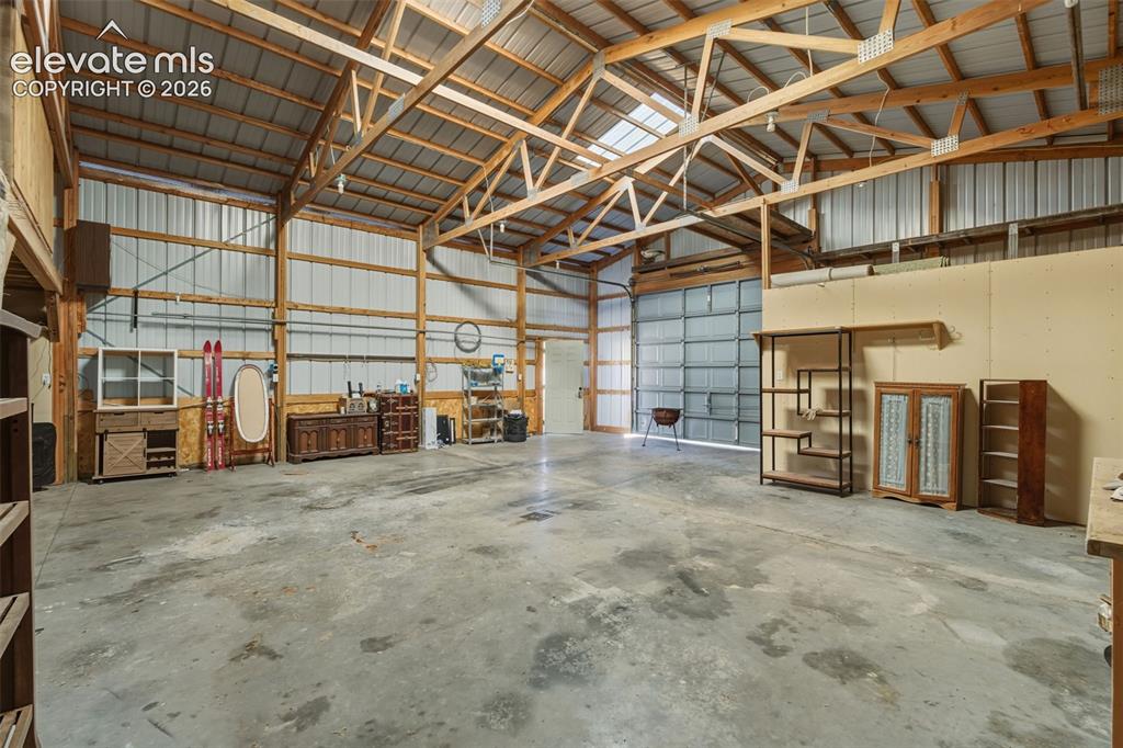 Image 12 of 43: Spacious interior with exposed wood beam framing, corrugated metal walls, c