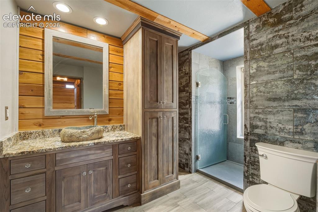 Image 13 of 40: Wood-paneled wall with recessed lighting, stone vessel sink, granite counte