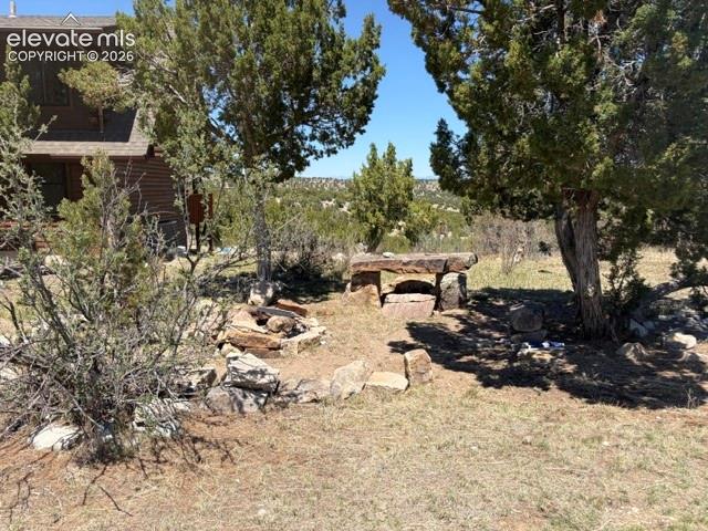 Image 14 of 43: Log cabin exterior, natural stone fire pit, built-in stone seating, mature 