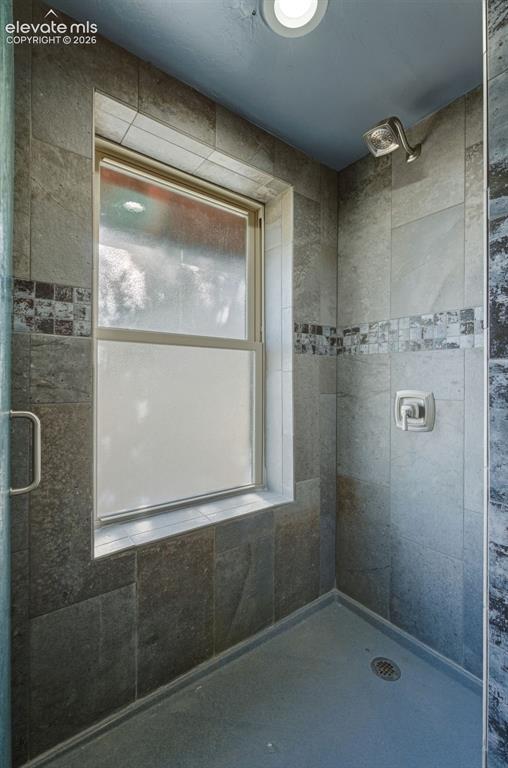 Image 14 of 40: Tiled shower enclosure featuring a frosted window, decorative mosaic tile a