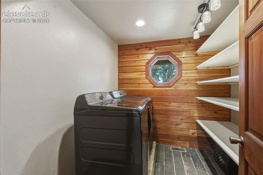 Image 15 of 40: Wood-paneled accent wall with an octagonal window, built-in shelving, track