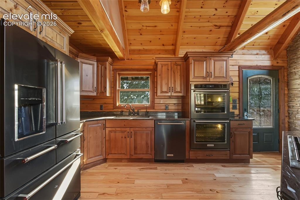 Image 2 of 40: Wood-finish flooring, wood plank walls, exposed beam ceiling, dark countert