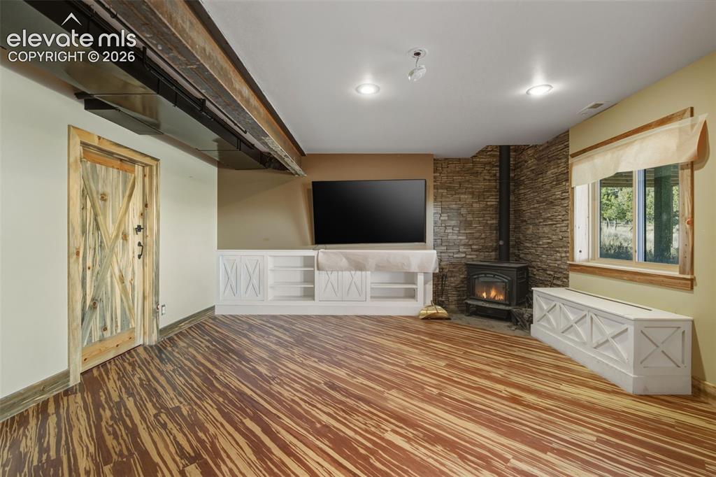 Image 23 of 40: Wood-finish flooring, built-in white cabinetry, stone veneer accent wall, w