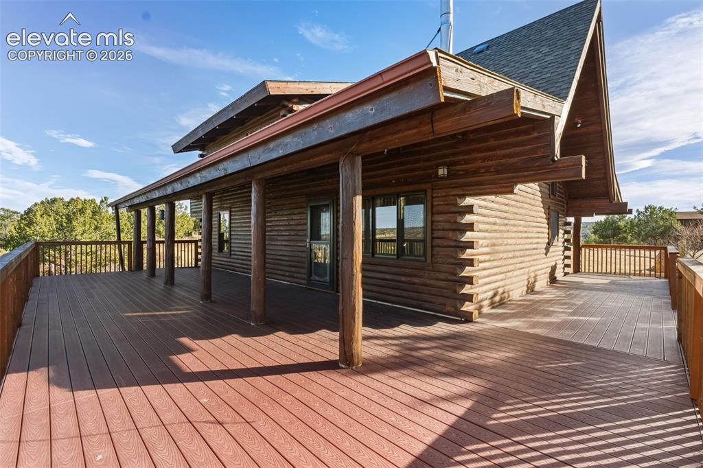 Image 28 of 40: Expansive wrap-around deck featuring composite decking and a log cabin exte