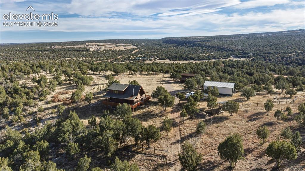 Image 3 of 43: Wood-sided residence with an expansive wood deck, surrounded by mature tree