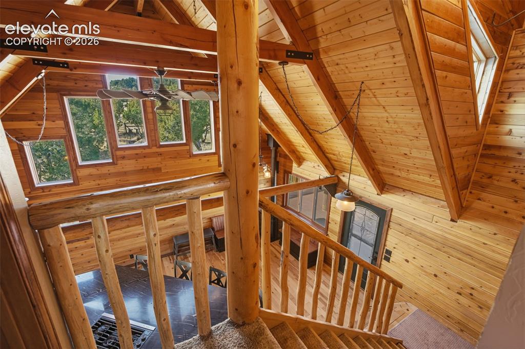 Image 3 of 40: Vaulted wood-paneled ceilings, exposed wood beams, log staircase with wood