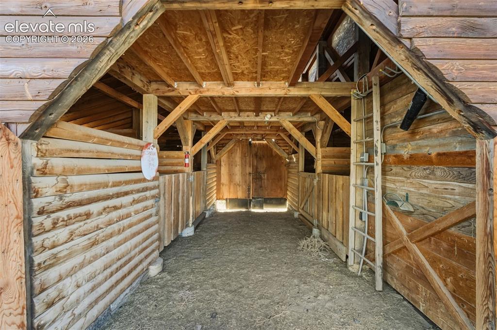 Image 30 of 40: Exposed wood beam construction, natural wood plank walls, and a gravel floo