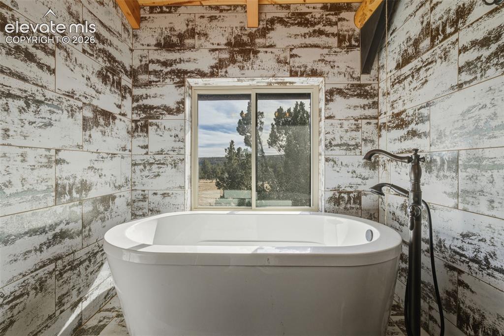 Image 32 of 43: Freestanding soaking tub with a floor-mounted bath filler, set against dist