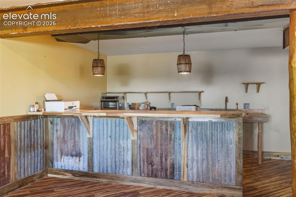 Image 39 of 43: Recycled corrugated metal bar front, wood-finish flooring, exposed wood bea