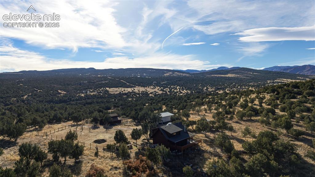 Image 39 of 40: Expansive natural landscape with scattered trees, mountainous backdrop, and
