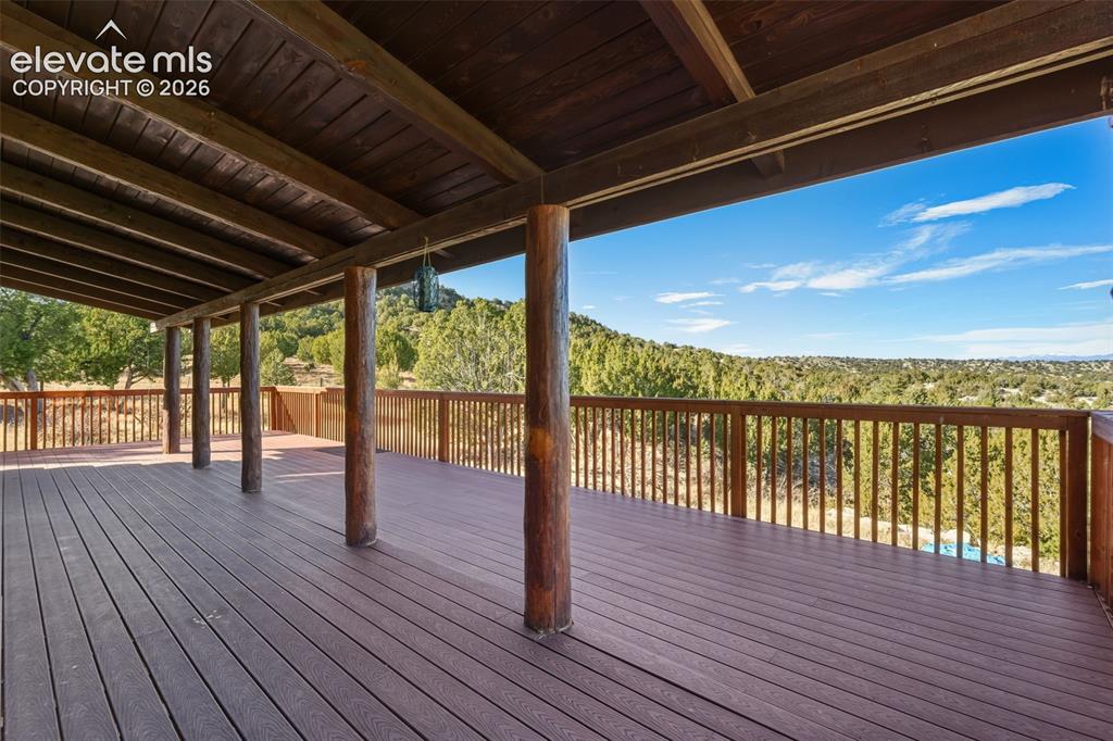 Image 41 of 43: Expansive covered deck with wood-finish flooring, natural wood posts, and a