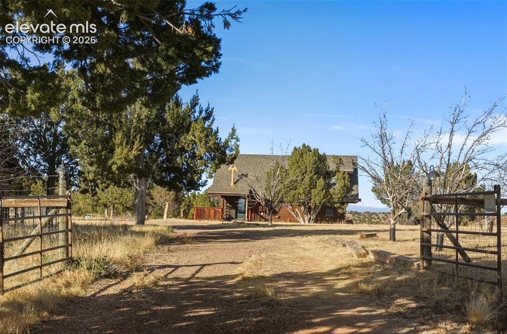 Image 5 of 40: Gated entry with a gravel drive leading to the property