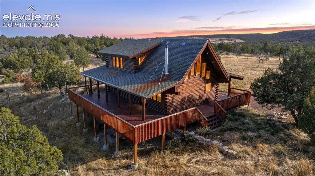 Image 6 of 40: Log home exterior featuring a pitched roof, full-length deck, and a promine