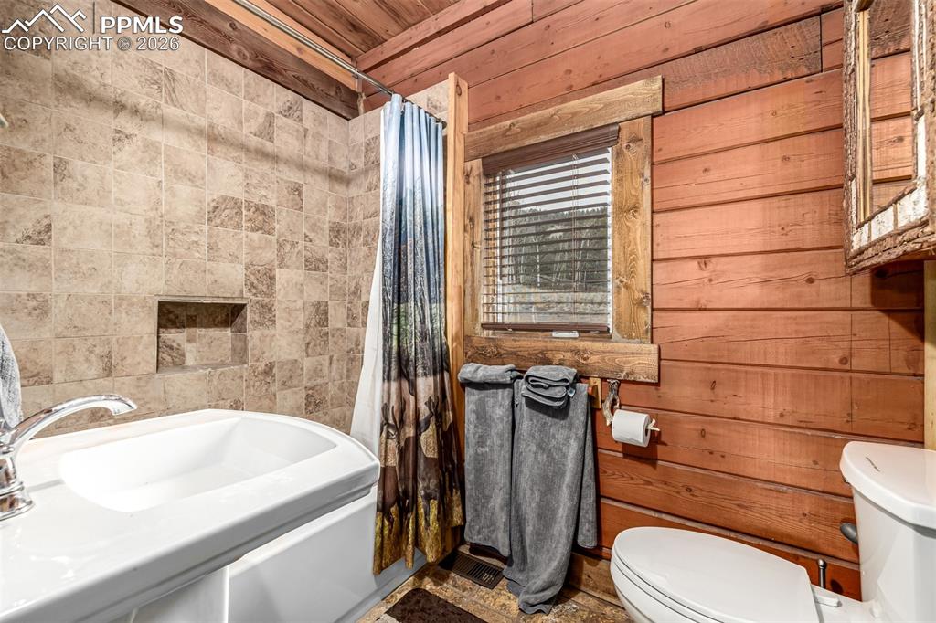 Image 30 of 35: Full bath featuring shower / bath combo, wooden walls, and wooden ceiling
