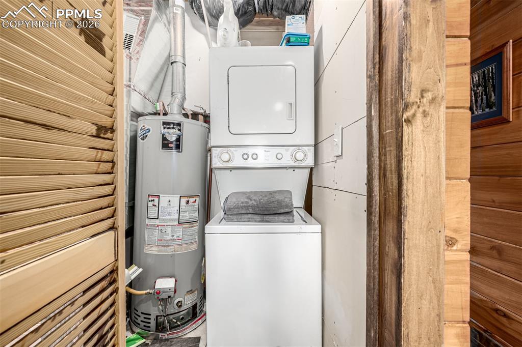 Image 31 of 35: Laundry area with water heater and stacked washer and clothes dryer