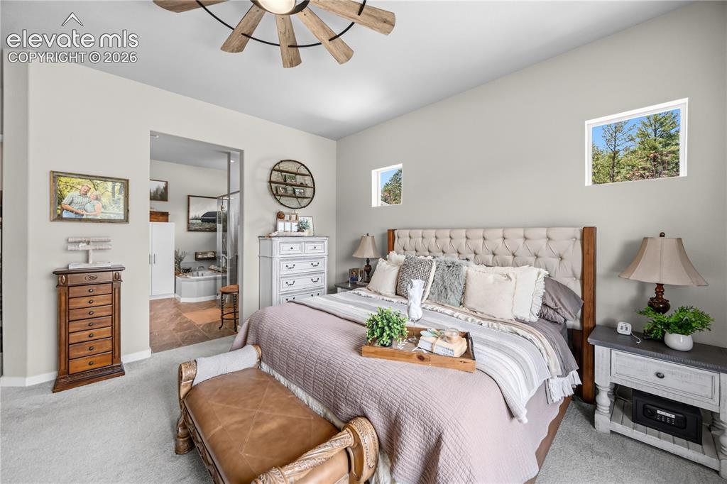 Image 18 of 50: Carpeted bedroom featuring a tufted headboard, recessed windows, a rustic c
