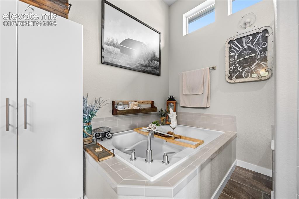 Image 22 of 50: Built-in soaking tub featuring a tile surround, chrome fixtures, and a high
