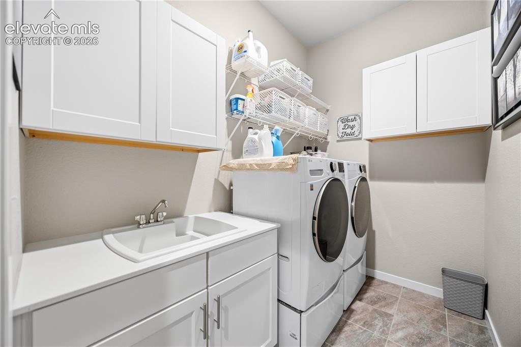 Image 30 of 50: Dedicated laundry space featuring a utility sink, white shaker-style cabine
