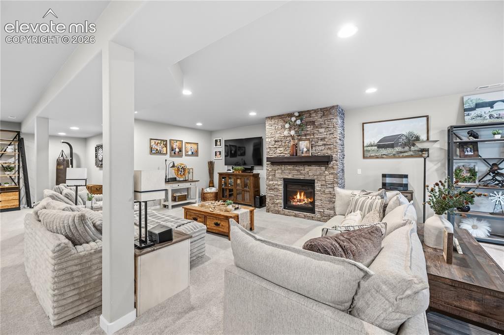 Image 32 of 50: Spacious interior featuring a stone-clad fireplace with a wood mantel, rece
