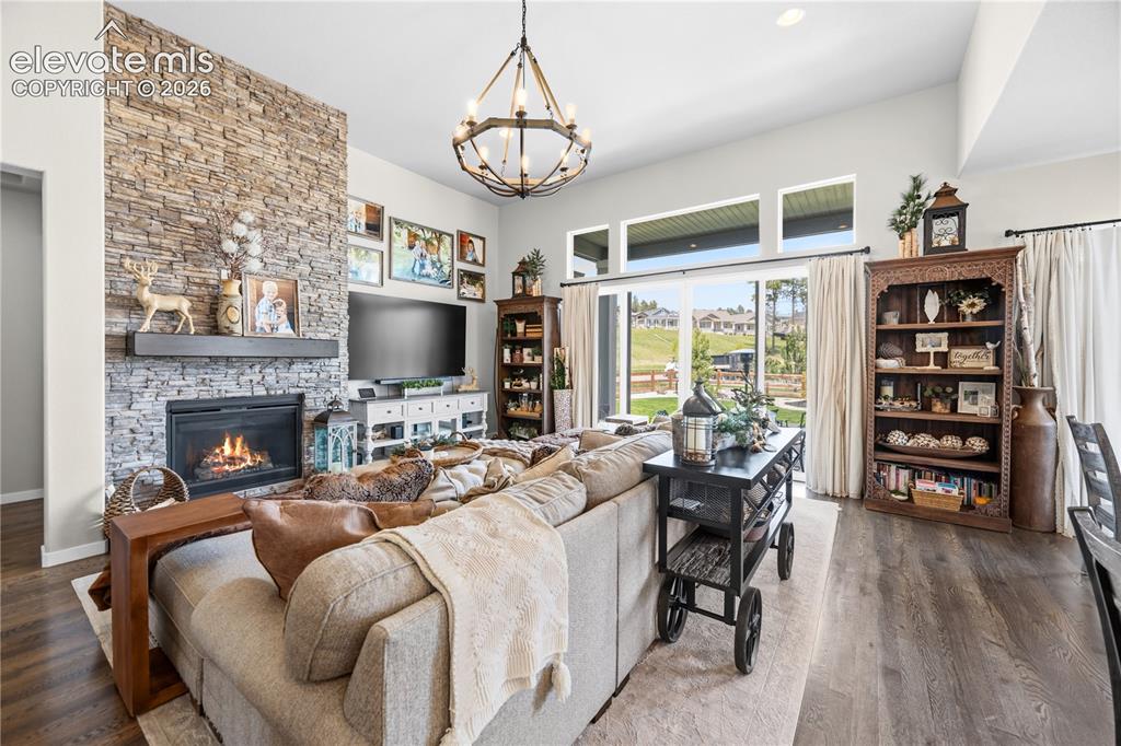 Image 4 of 50: Spacious living area featuring a stone-clad fireplace with a dark wood mant