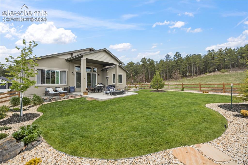 Image 47 of 50: Expansive backyard featuring a manicured lawn, a large concrete patio, and
