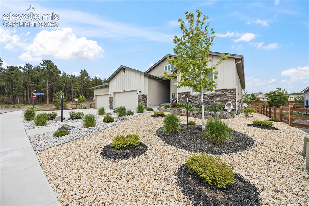 Image 49 of 50: Contemporary home with a two-car garage, stone and siding exterior, and a g
