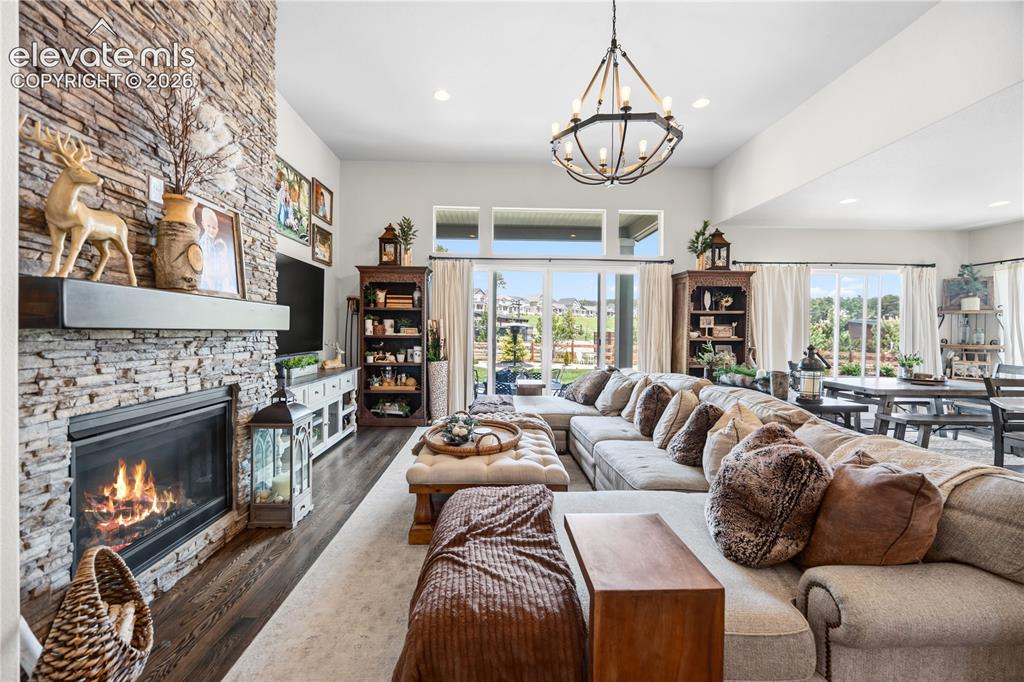 Image 5 of 50: Great room featuring a floor-to-ceiling stacked stone fireplace with a dark