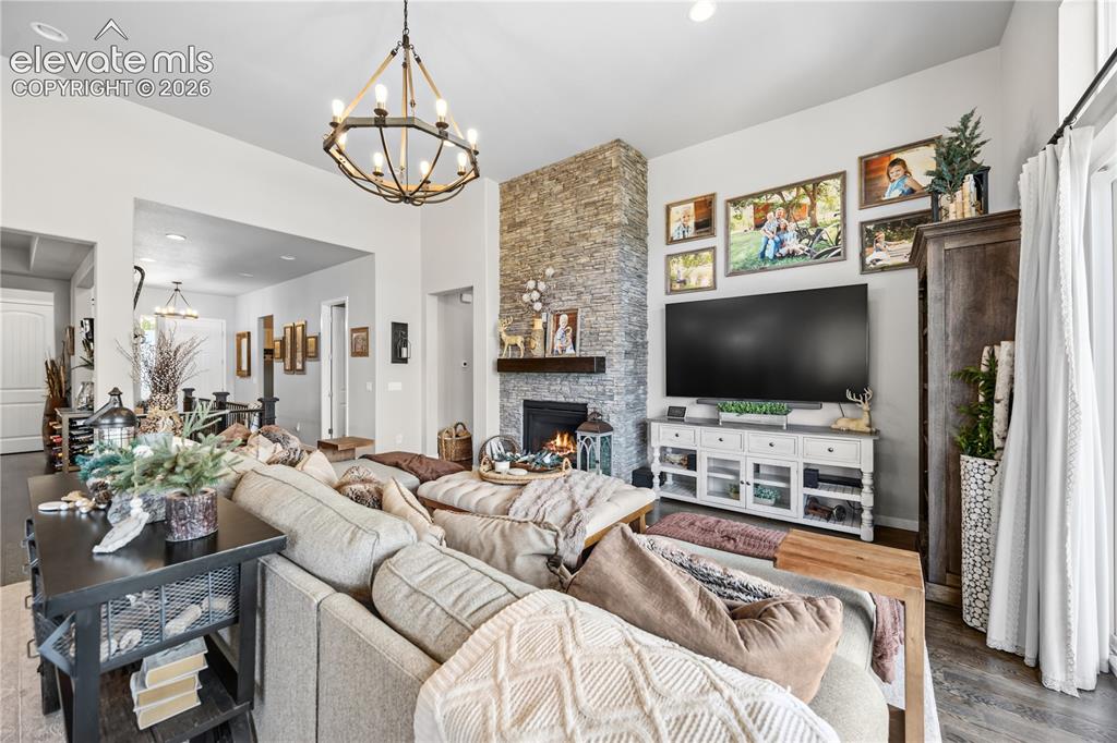 Image 6 of 50: Spacious living area featuring a stone-clad fireplace, high ceilings, an op