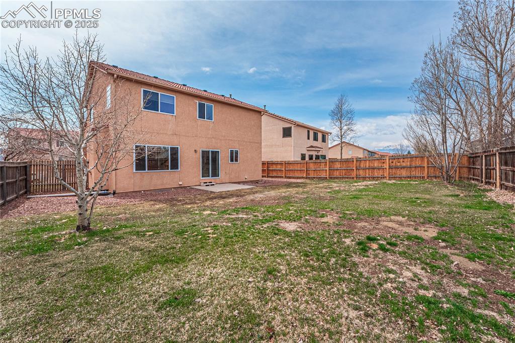 Image 43 of 47: Back of property featuring a fenced backyard, a lawn, stucco siding, and a 