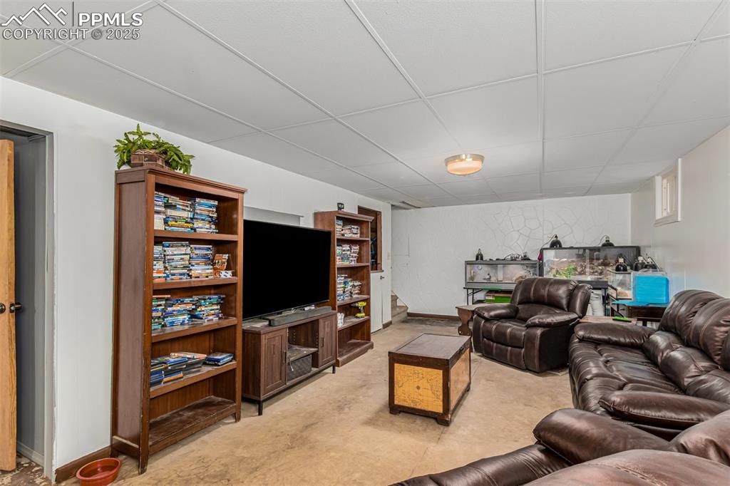 Image 7 of 17: Living area with a paneled ceiling and concrete floors