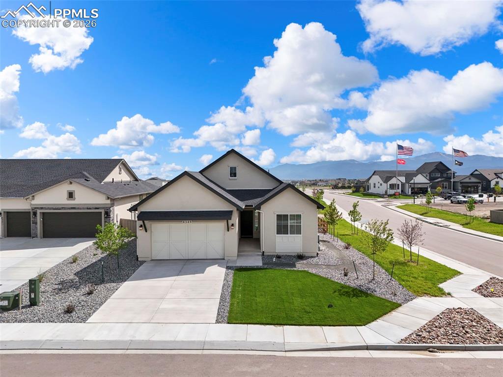 Caption: View of front facade featuring a garage, driveway, stucco siding, a front lawn, and a residential vi