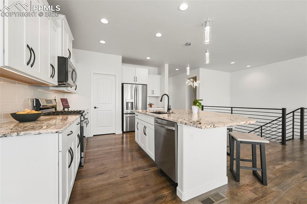 Image 13 of 38: Kitchen with stainless steel appliances, dark wood-type flooring, decorativ