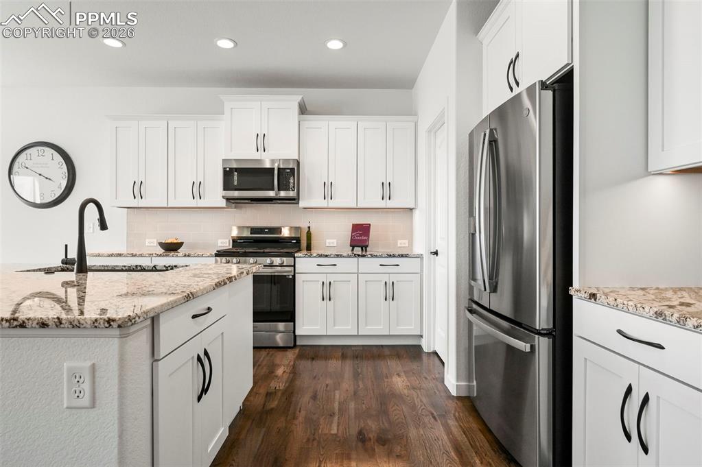 Image 14 of 38: Kitchen with stainless steel appliances, dark wood-style flooring, tasteful