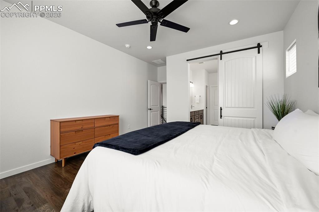 Image 21 of 38: Bedroom with dark wood-type flooring, a barn door, recessed lighting, conne