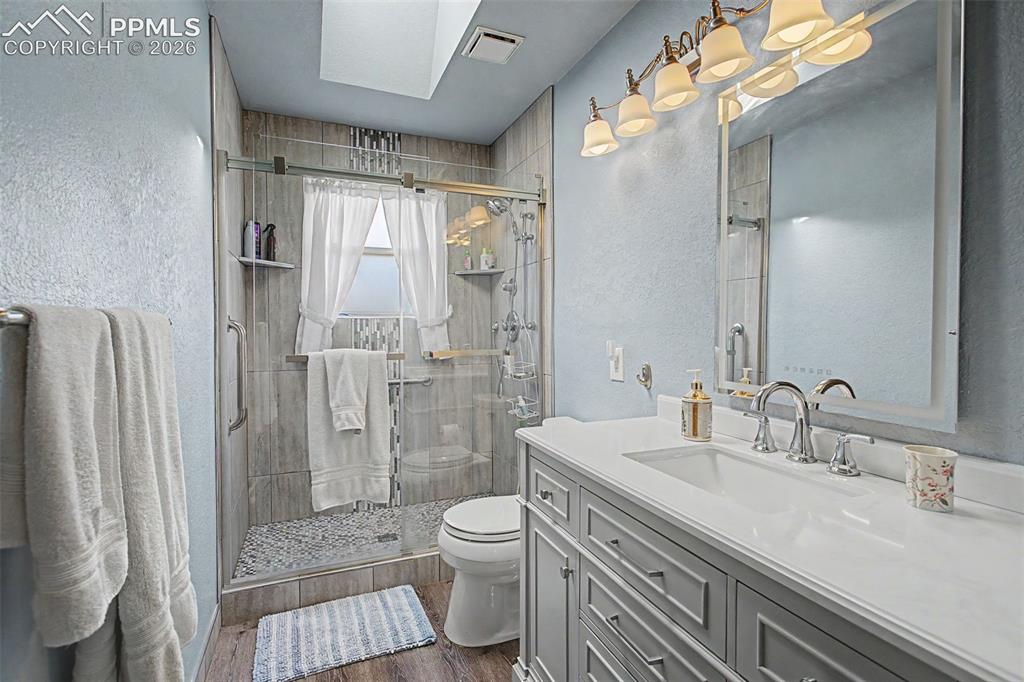 Image 32 of 46: Upper level 3/4 bathroom, with skylight and floor-to-ceiling tiled walk-in