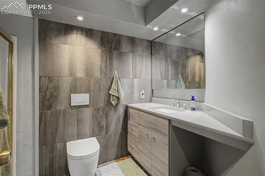 Image 36 of 46: Basement 3/4 bathroom, floor-to-ceiling tiled accent wall and walk-in showe