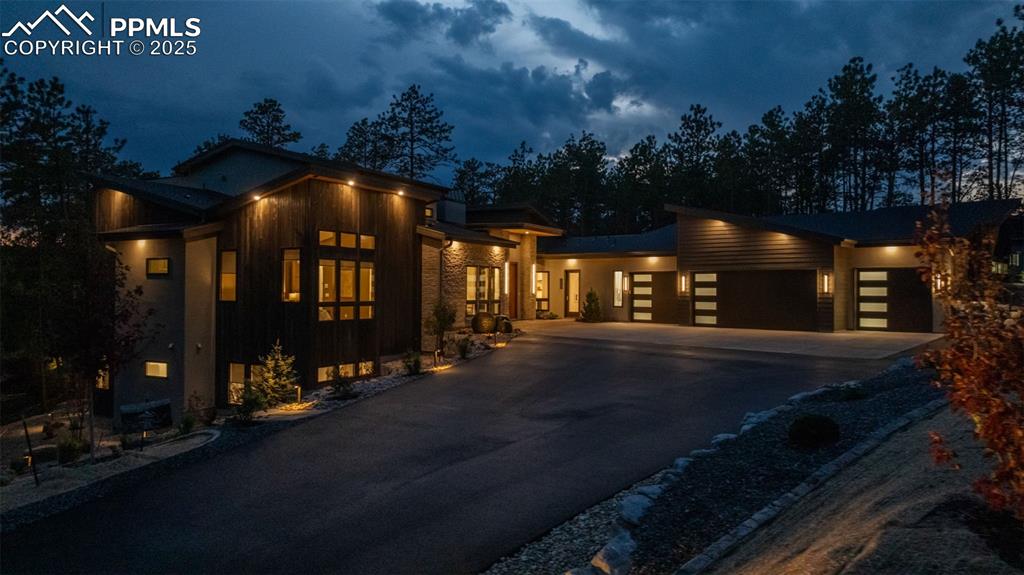 Image 2 of 50: Modern home featuring a garage, asphalt driveway, and board and batten sidi